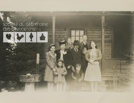 Portrait d’une famille inconnue devant une cabane